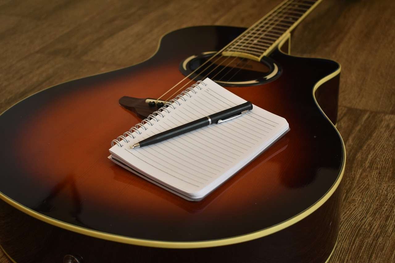 songwriting-2757636_1280 Acoustic guitar with writing pad and pencil